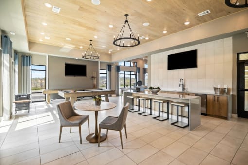 a large lobby with tables and chairs and a kitchen