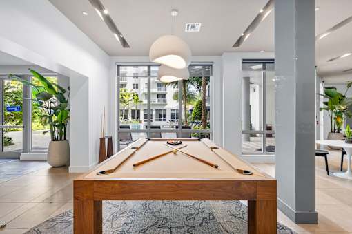 A pool table in the middle of a room with a view of the outside.