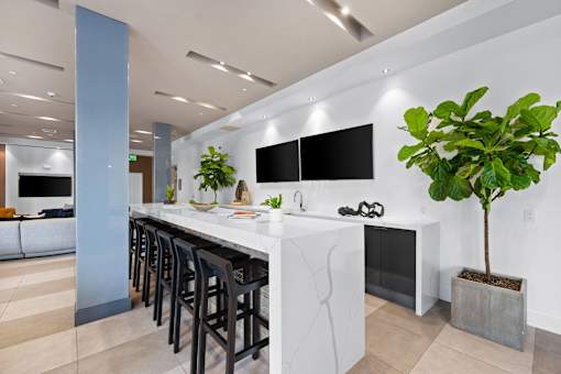 A kitchen with a white counter top and black bar stools.
