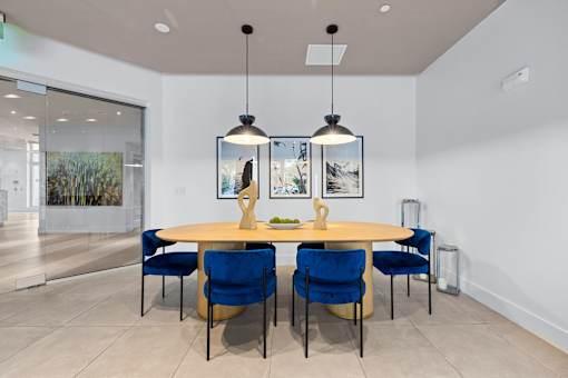 A dining room with a round table and blue chairs.