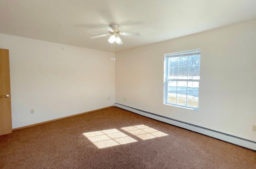 a spacious bedroom with baseboard heaters and a ceiling fan