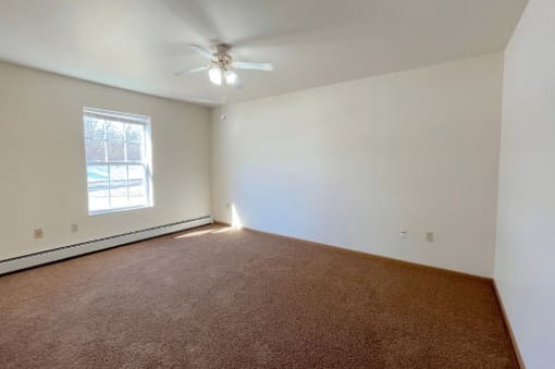 a bedroom with a ceiling fan, large window, and baseboard heater