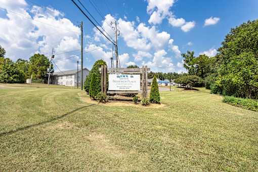 A sign in front of a grassy area that says "Residence Place".