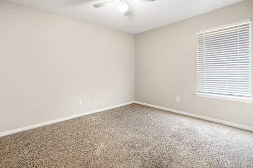 A room with a carpeted floor and a ceiling fan.