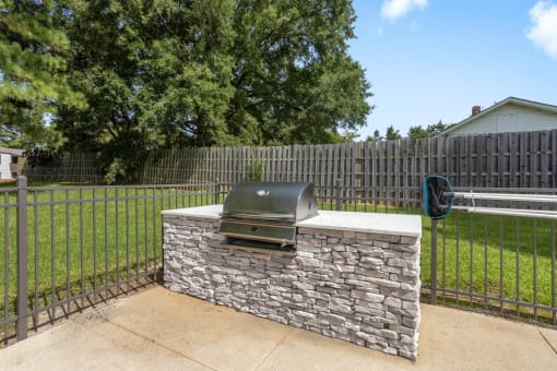 a stone outdoor grill in a backyard with a fence