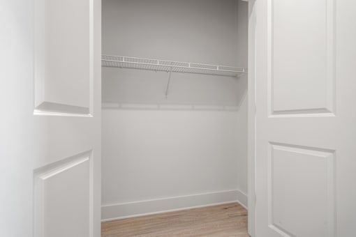 an empty closet in a home with white walls and wood floors