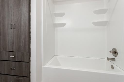 a bathroom with a white tub and a wooden cabinet