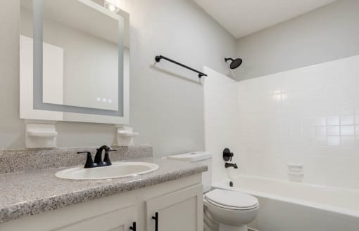 a bathroom with a smart mirror, sink vanity, toilet, and tub/shower