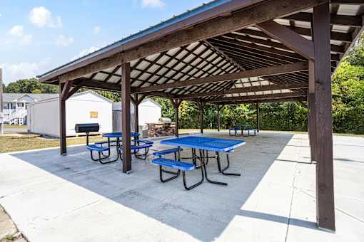 A covered picnic area with blue tables and benches.