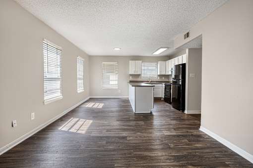 A kitchen area with a refrigerator, sink, and cabinets.