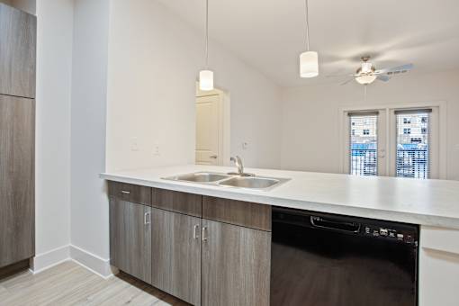 an empty kitchen with a sink and a ceiling fan