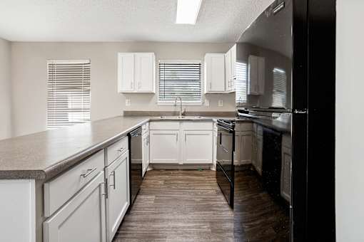 A kitchen with white cabinets and a black refrigerator.