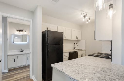 renovated kitchen with quartz countertops, black appliances, and a bathroom with a smart mirror