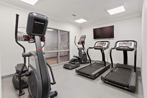 a gym with various exercise machines and a tv