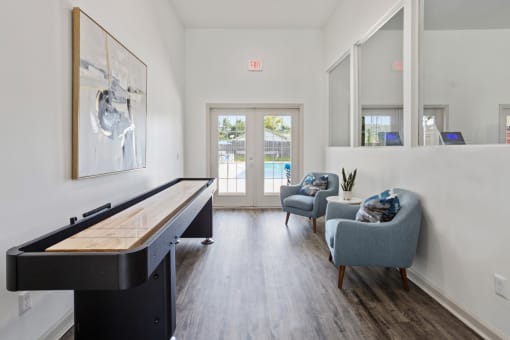 a living room with a piano and two chairs and a sliding glass door