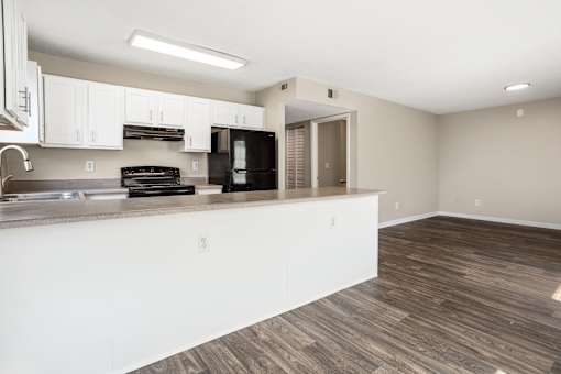 A kitchen with white cabinets and a black fridge.