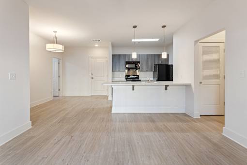 an open kitchen and living room with white walls and wood flooring