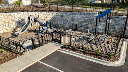 a playground with slides and benches in front of a stone wall