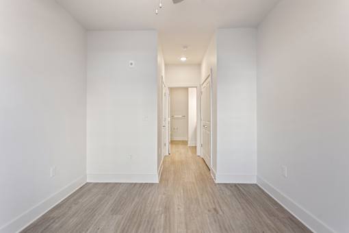 an empty room with white walls and wood floors