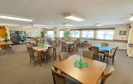 a large community room with many tables and chairs and a vending machine at Algonquin Manor