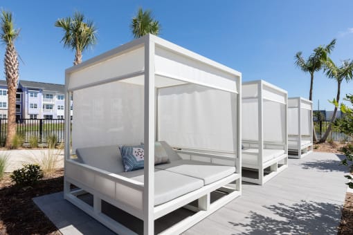 a row of white cabanas on Concorde's pooldeck with palm trees in the background