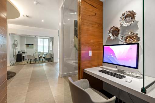 A modern home office with a wooden accent wall and a large monitor.