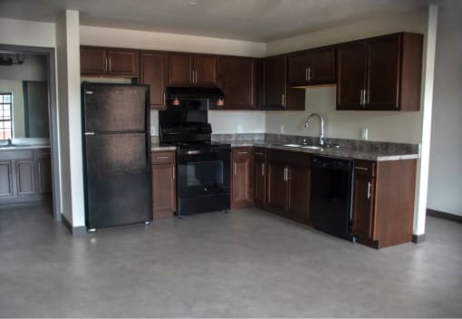 an empty kitchen with black appliances and wooden cabinets