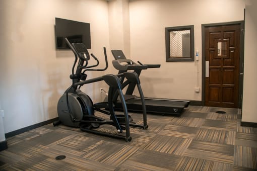 a gym with two treadmills and a tv in a hotel room