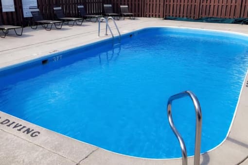 a large, blue swimming pool and a sundeck with lounge chairs