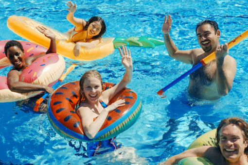a group of people in a swimming pool in inflatable pool floats