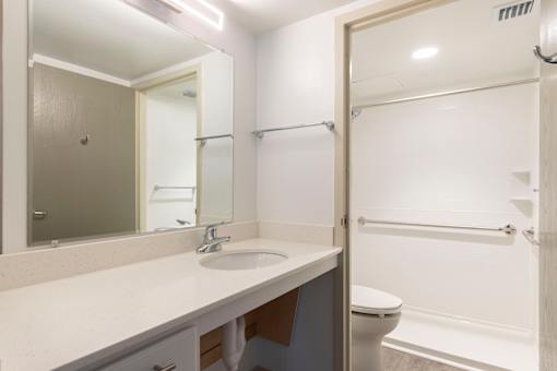A bathroom with a sink, mirror, toilet and bathtub.