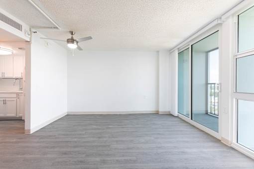 A room with a ceiling fan and a door leading to a kitchen.