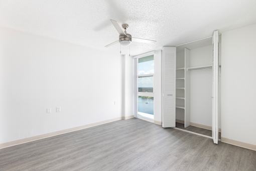 A room with a ceiling fan and a sliding door leading to a balcony.