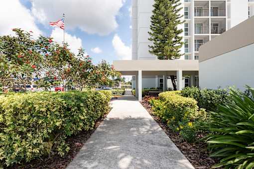 A pathway leads to a white building with a flag on top.