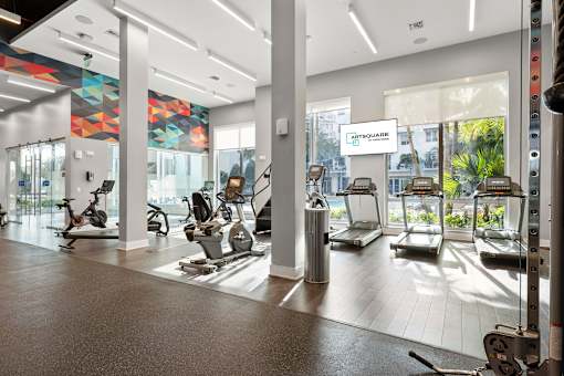 A gym with a variety of exercise equipment including treadmills, stationary bikes, and rowing machines.