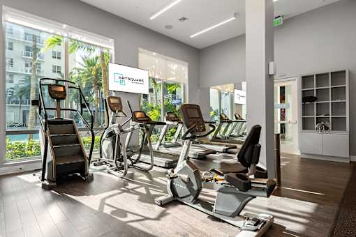 A gym with a variety of equipment including treadmills, stationary bikes, and elliptical machines.