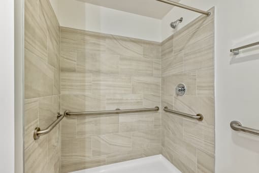 a spacious shower with grab bars in a bathroom