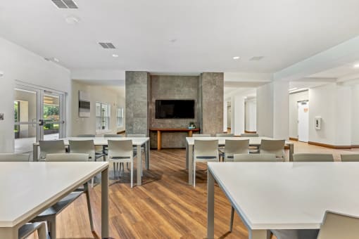 a dining room with tables and chairs and a living room with a television