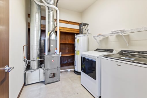 an apartment home utility room with a washer, dryer, built-in shelving, hot water heater and HVAC at Horicon School