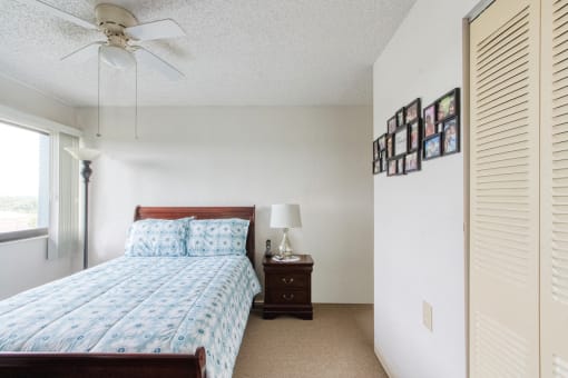 bedroom with large window, ceiling fan, closet, and model furnishings