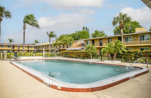 a swimming pool in front of a hotel with palm trees