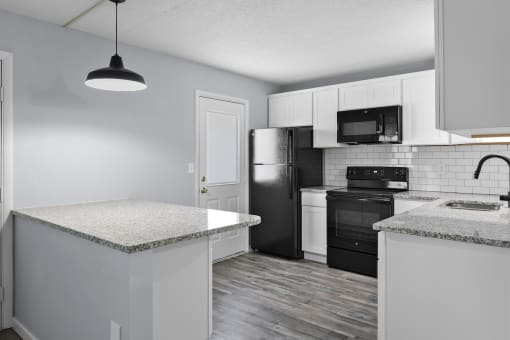 a kitchen with white cabinets and black appliances