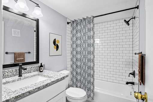 A bathroom with a black and white shower curtain.