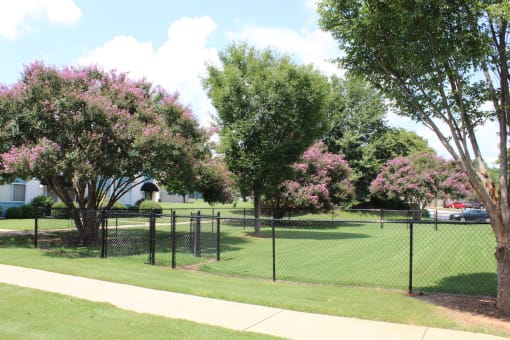 fenced dog park surrounded by mature trees  at Huntsville Landing Apartments, Huntsville, Alabama