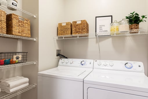 a white washer and dryer in a laundry room with baskets on shelves above