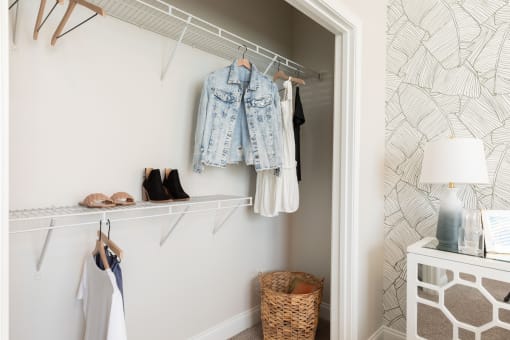a closet with clothes hanging on the wall and a closet door with shoes on it