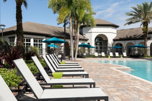 a pool with lounge chairs and a building in the background