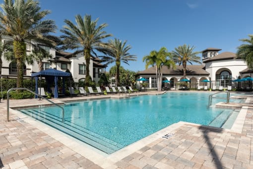 a large swimming pool with palm trees in front of a building