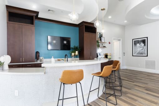 a kitchen with a bar and stools and a blue wall