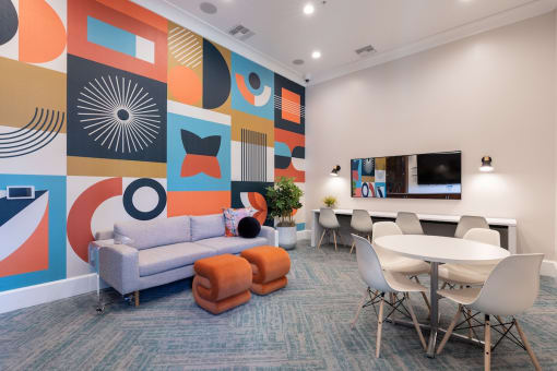 a room with a couch table and chairs and a wall with a mural